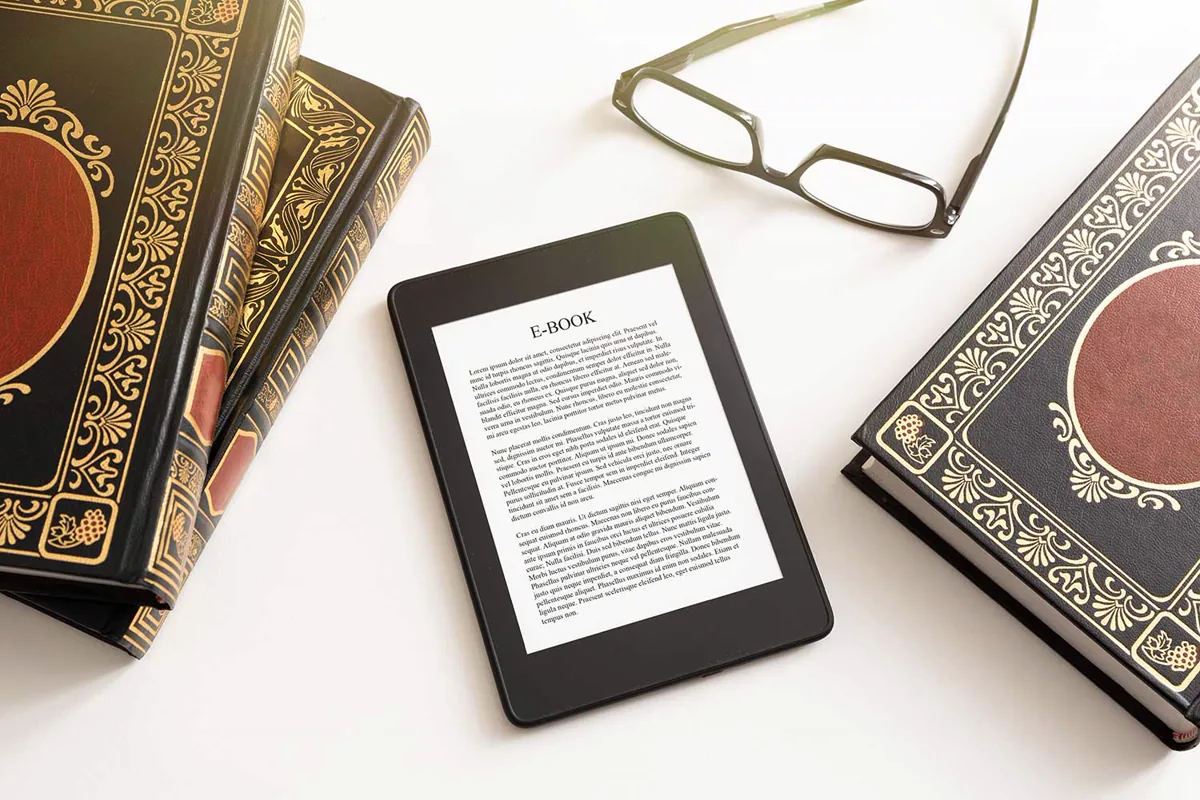 E-Reader, Bücher und Lesebrille auf einem Tisch